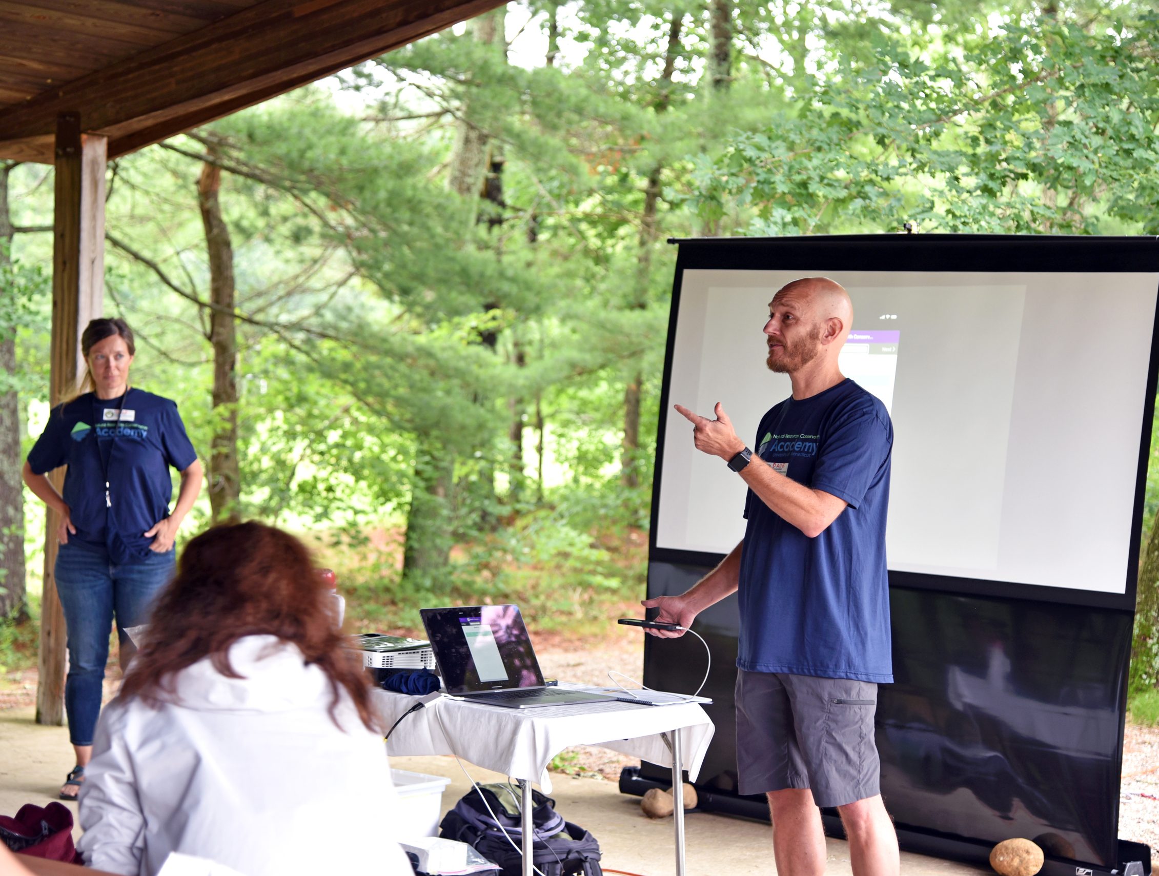 man and woman doing an outdoor presentation to a group of students